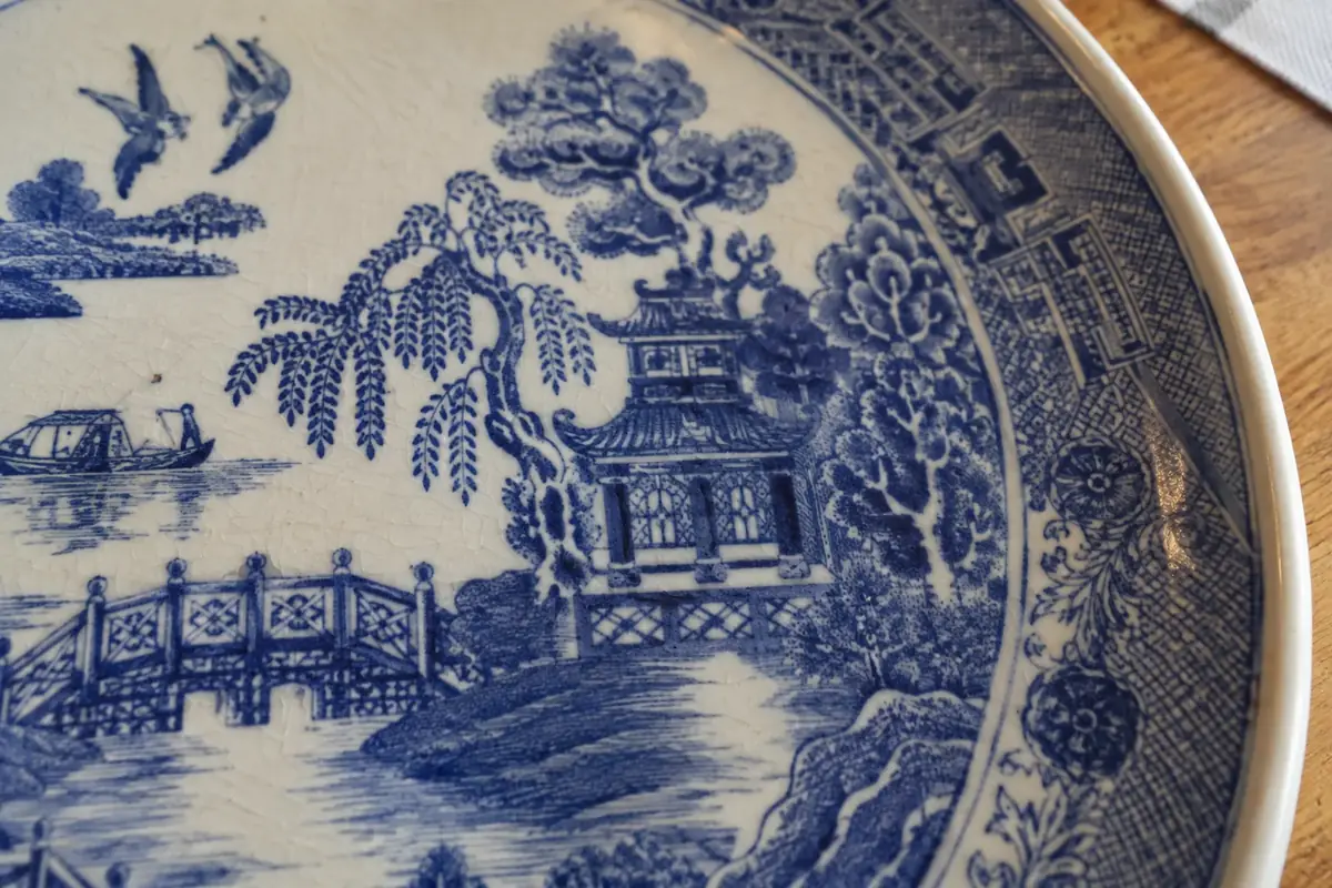 Close-up of blue transfer printing on a Willow plate showing fine lines and crazing in the glaze
