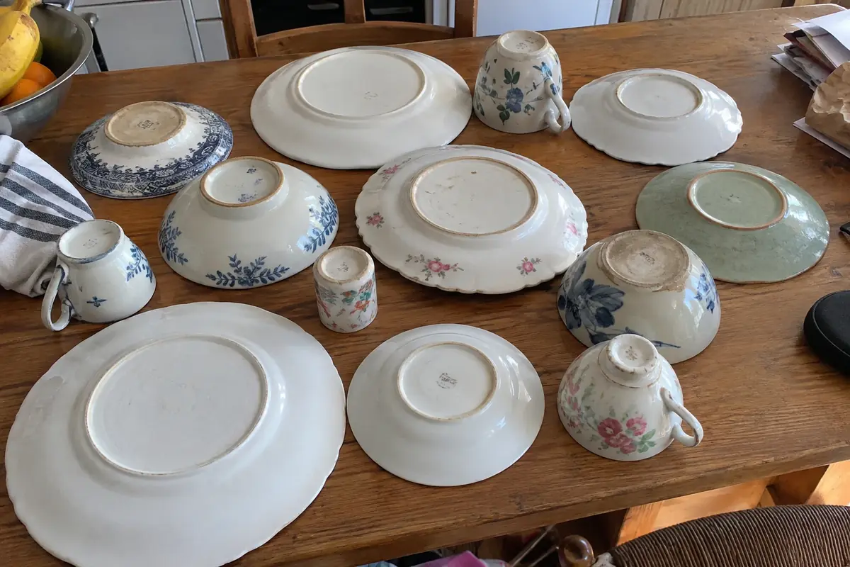 Assorted plates and cups turned upside down on a kitchen table to show their bases