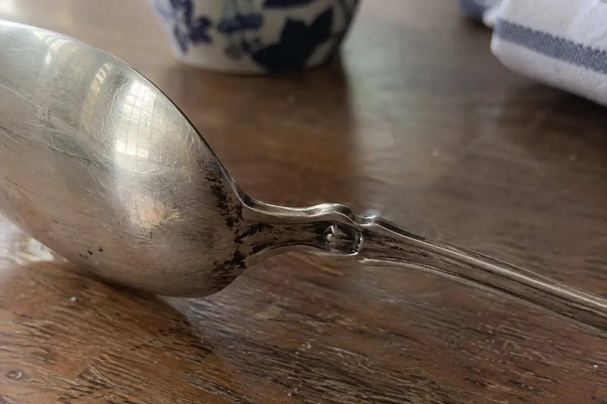 Close view of the back of a sterling spoon handle with shallow stamped impressions catching low-angle light