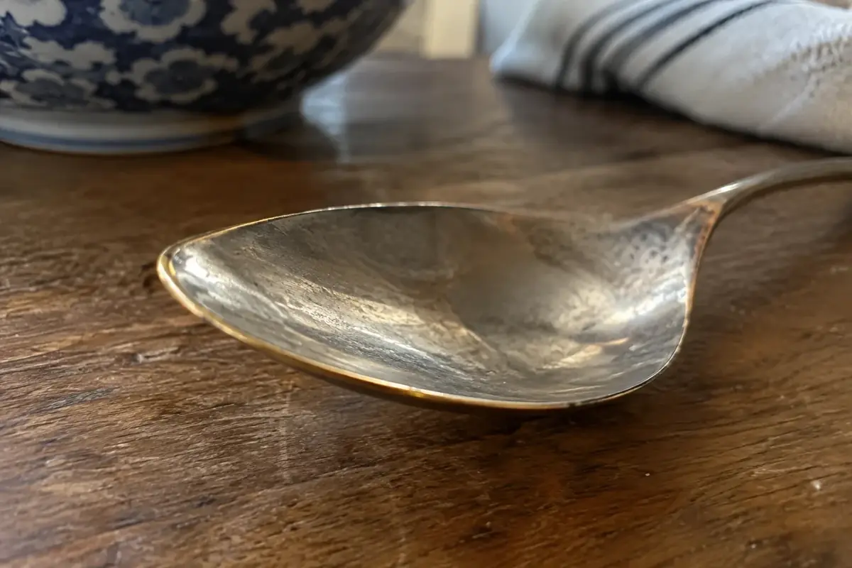 Close-up of a plated spoon bowl where the silver has worn through to yellowish base metal